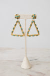 Gold triangle dangle earrings with turquoise blue rectangular stones and round turquoise coin posts, displayed on a cream textured stand.