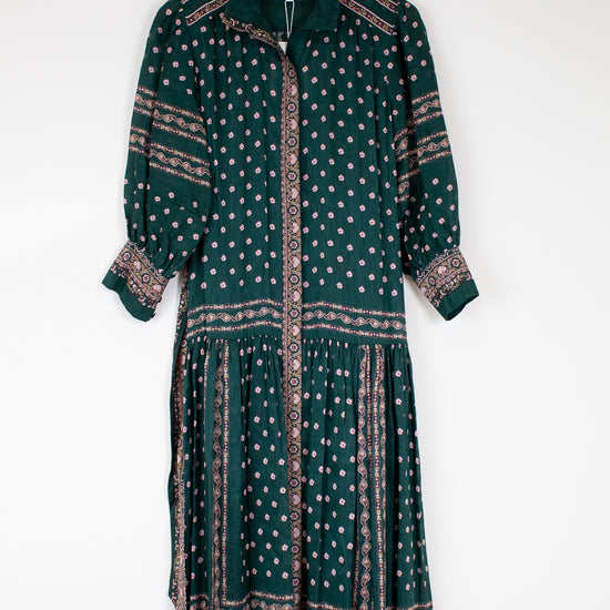 Green patterned dress on a hanger against a white background