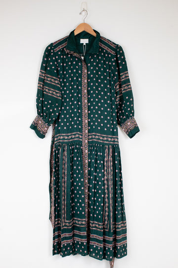 Green patterned dress on a hanger against a white background