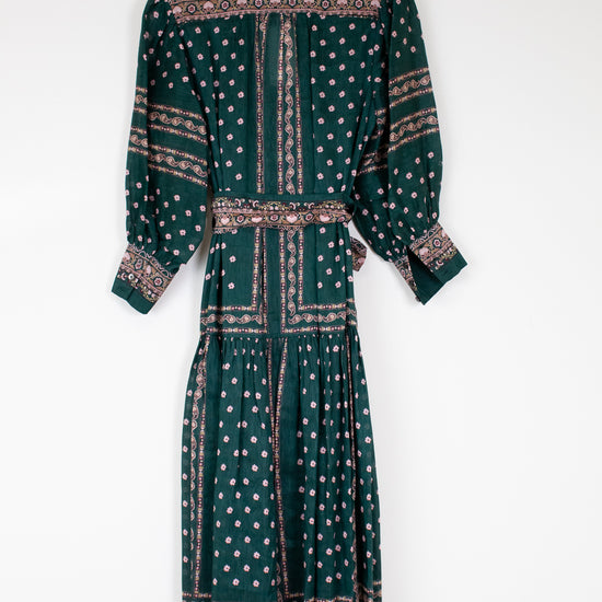 Green patterned dress on a hanger against a white background