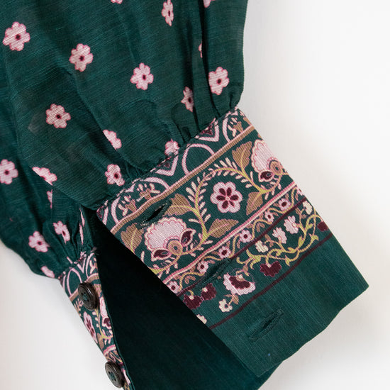 Green fabric with pink floral patterns on a white background