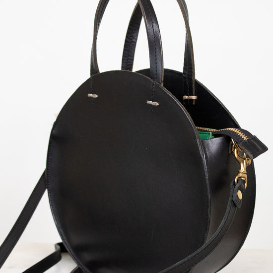 Black leather handbag with a strap on a white background