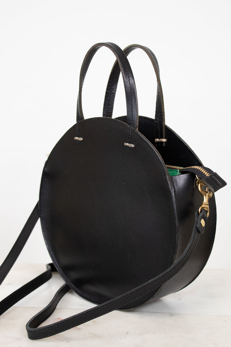 Black leather handbag with a strap on a white background