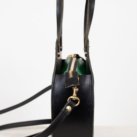 Black leather handbag with gold zipper on a white background