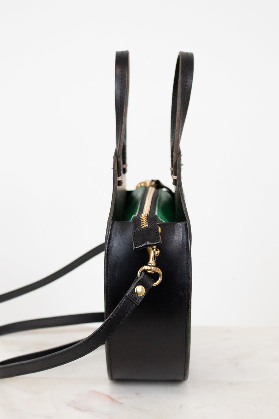 Black leather handbag with gold zipper on a white background