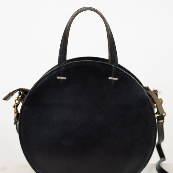 Black round handbag with gold accents on a white background
