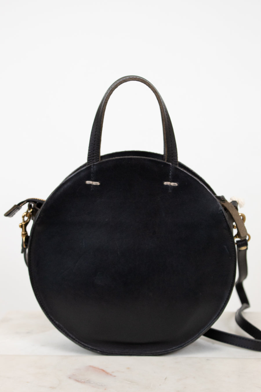 Black round handbag with gold accents on a white background