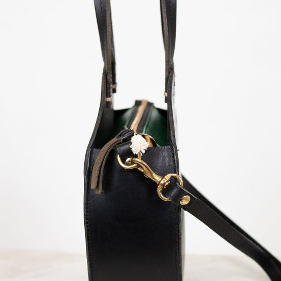 Black handbag with gold zipper on a white background