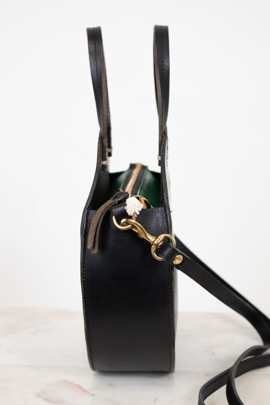 Black handbag with gold zipper on a white background