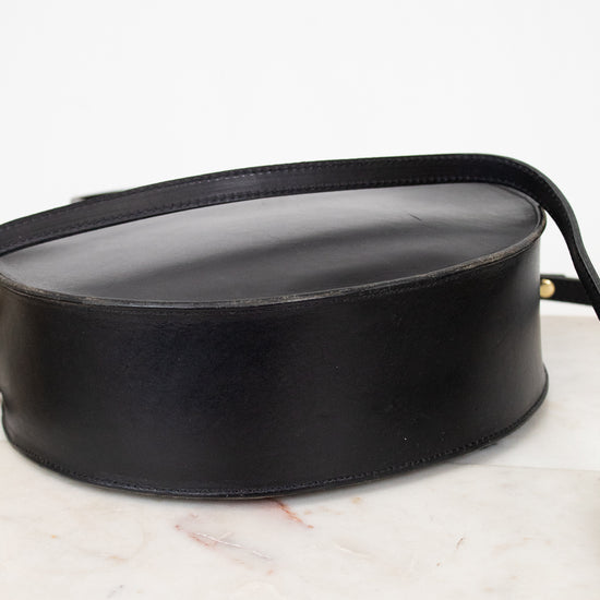 Bottom of black leather handbag on a marble surface