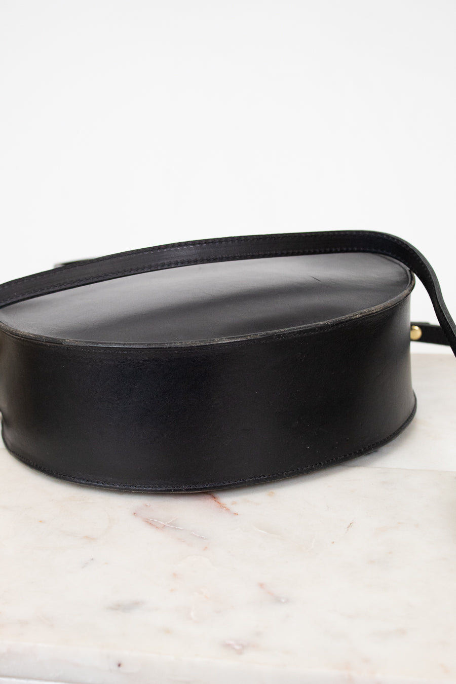 Bottom of black leather handbag on a marble surface
