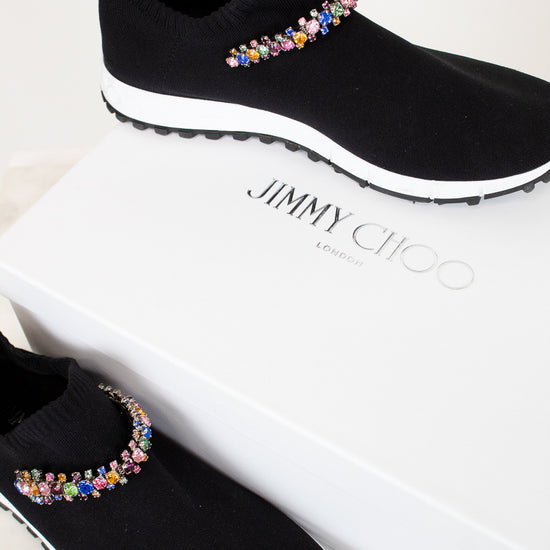 Black slip-on shoes with colorful embellishments on a white box with 'Jimmy Choo' branding.