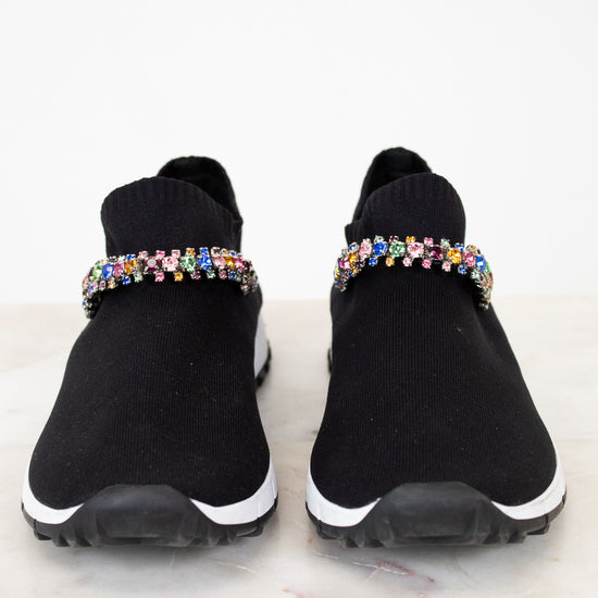 Black slip-on sneakers with colorful rhinestone embellishments on a white background