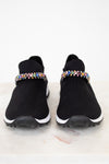 Black slip-on sneakers with colorful rhinestone embellishments on a white background