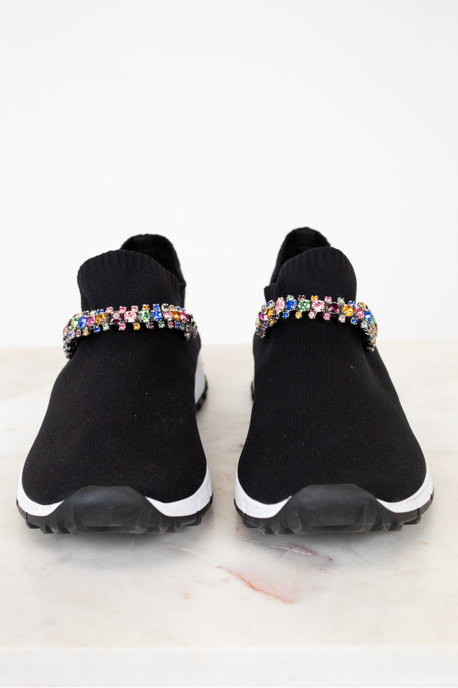 Black slip-on sneakers with colorful rhinestone embellishments on a white background
