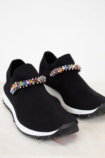 Black slip-on sneakers with colorful embellishments on a white background