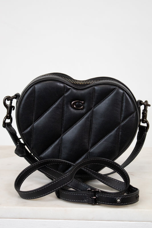 Black quilted heart-shaped handbag with a brand logo on a white background