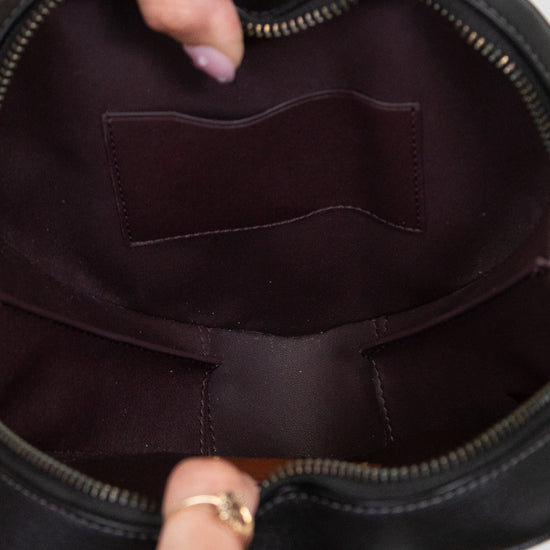 Close-up of a black handbag with a person's hand holding it open.