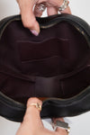 Close-up of a black handbag with a person's hand holding it open.