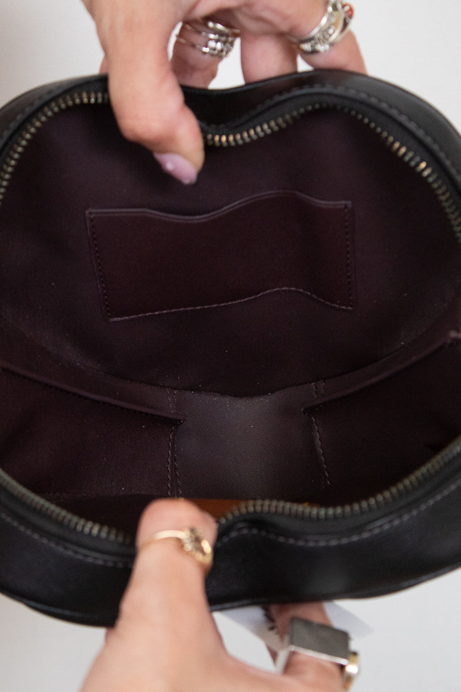 Close-up of a black handbag with a person's hand holding it open.