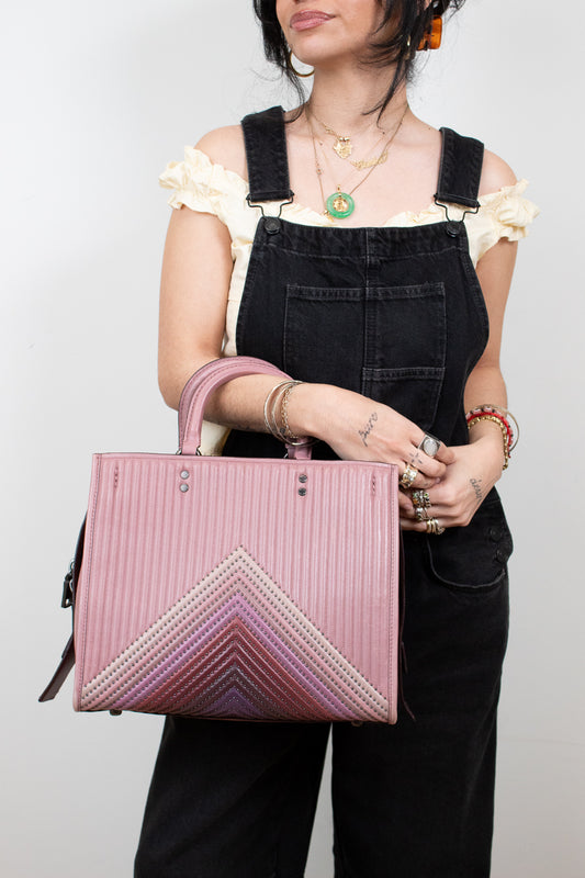 Person holding a pink handbag with a chevron pattern against a plain background
