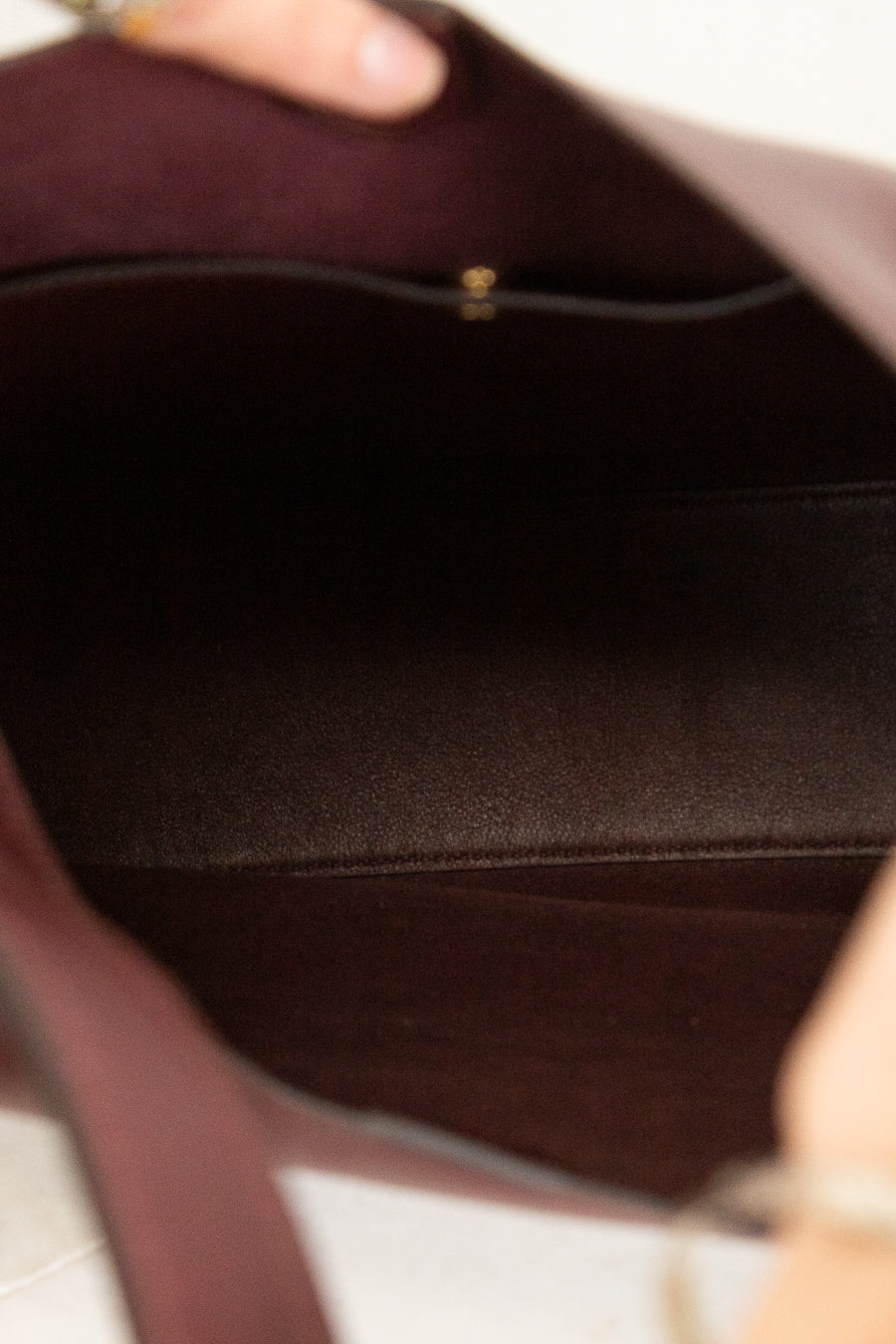 Close-up of a maroon leather handbags interior with a gold clasp.