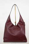 Maroon handbag with gold zipper on a white background