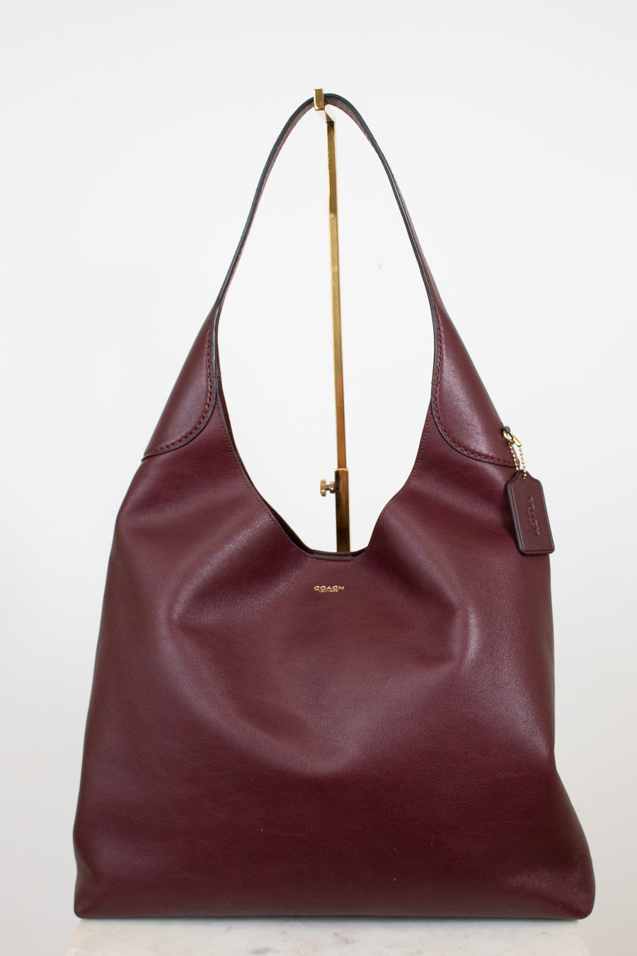 Maroon handbag with gold zipper on a white background