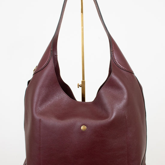 Maroon leather handbag with gold accents on a white background