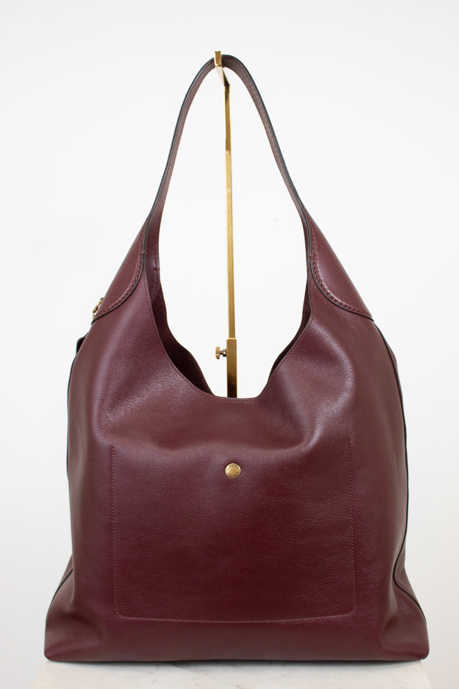 Maroon leather handbag with gold accents on a white background