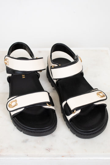 Black and white sandals with gold accents on a marble surface