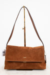 A brown suede Coach shoulder bag with a flap closure and a long shoulder strap, displayed on a stand against a white background.