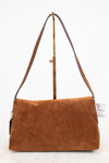A brown suede shoulder bag with a long brown leather strap and a gold-tone metal stand, photographed against a clean white background.