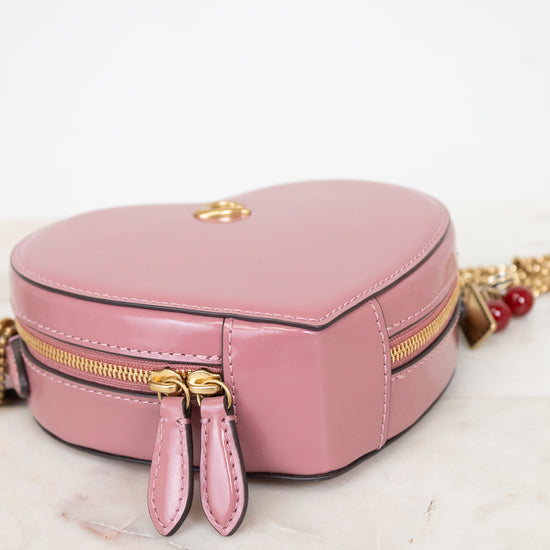 Pink heart-shapehandbag with gold zipper on a white surface