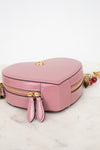 Pink heart-shapehandbag with gold zipper on a white surface