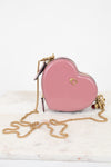 Pink heart-shaped handbag with gold chain on a white marble surface