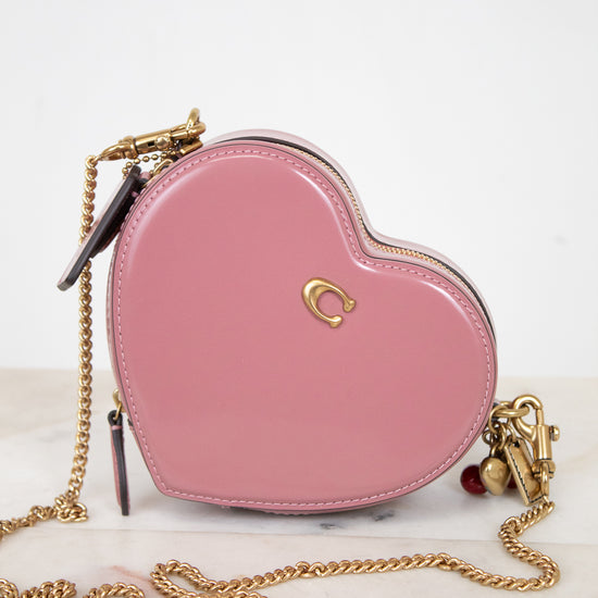 Pink heart-shaped handbag with gold chain on a white background