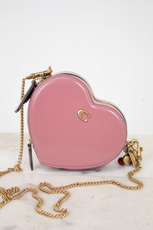 Pink heart-shaped handbag with gold chain on a white background