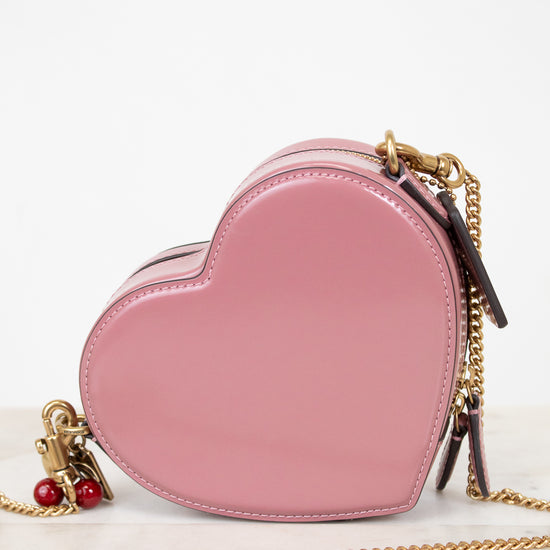 Pink heart-shaped handbag with gold chain on a white background