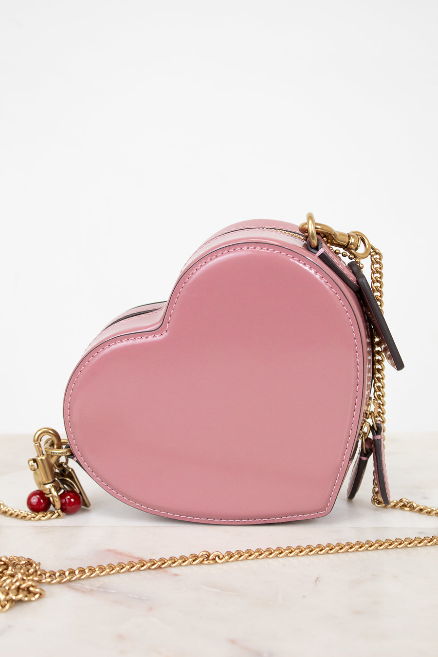 Pink heart-shaped handbag with gold chain on a white background