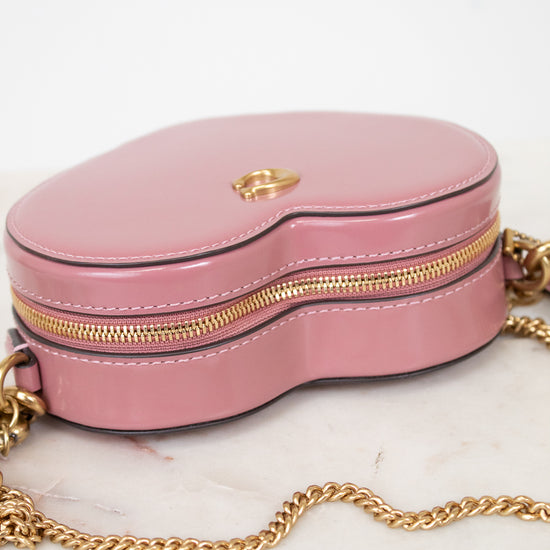 Pink handbag with gold chain on a marble surface