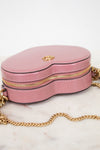 Pink handbag with gold chain on a marble surface