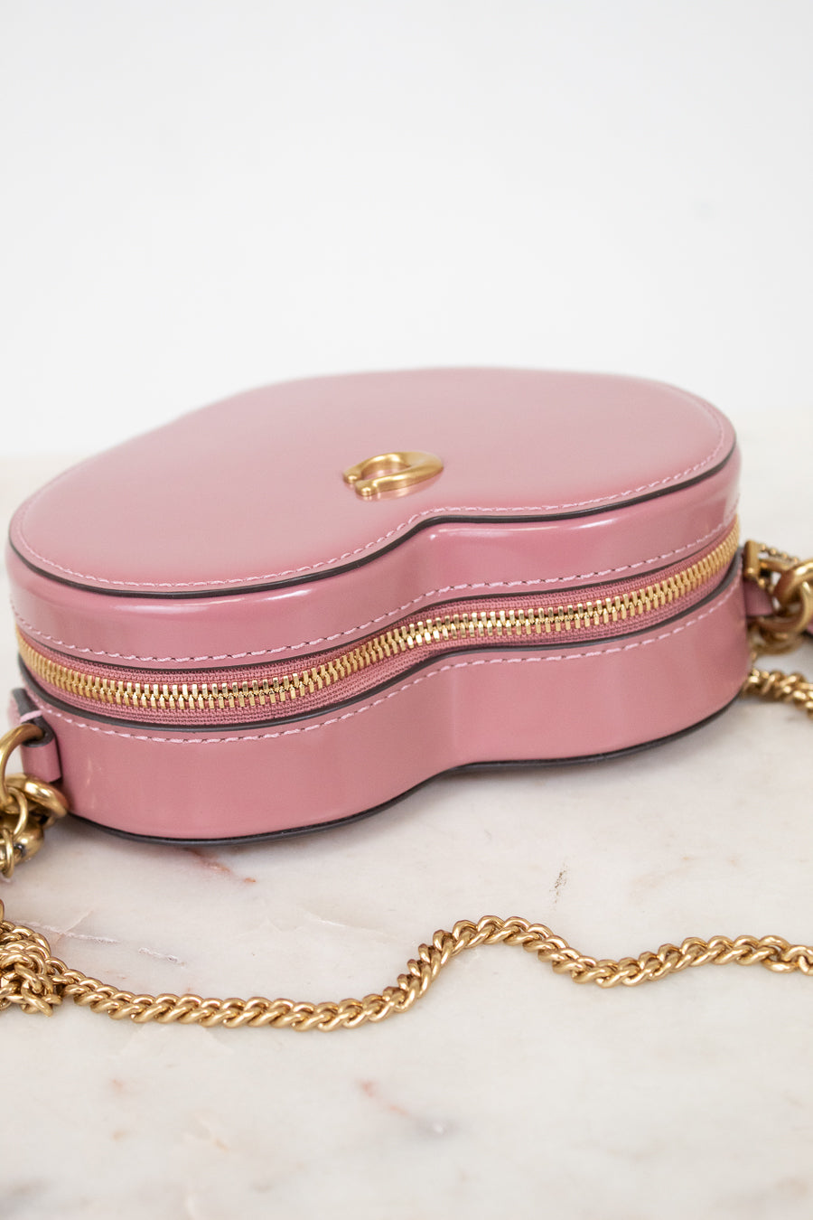 Pink handbag with gold chain on a marble surface