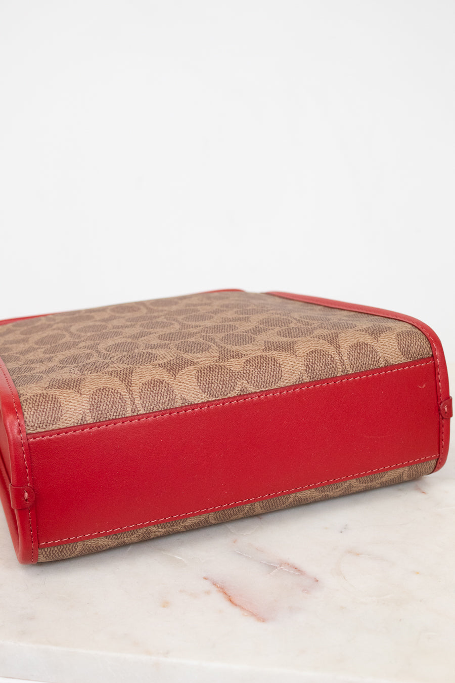 Red base of purse with brown patterned top section on a white surface
