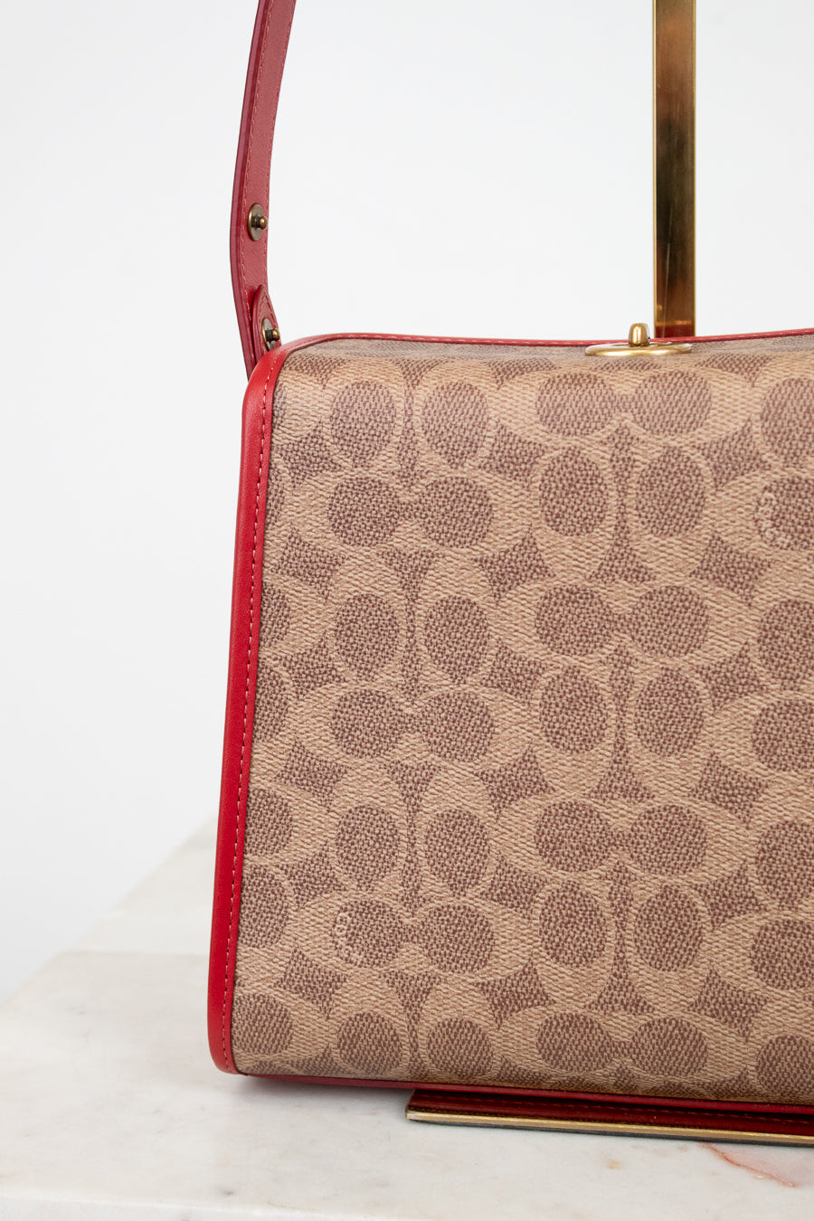 Coach handbag with red accents on a white background
