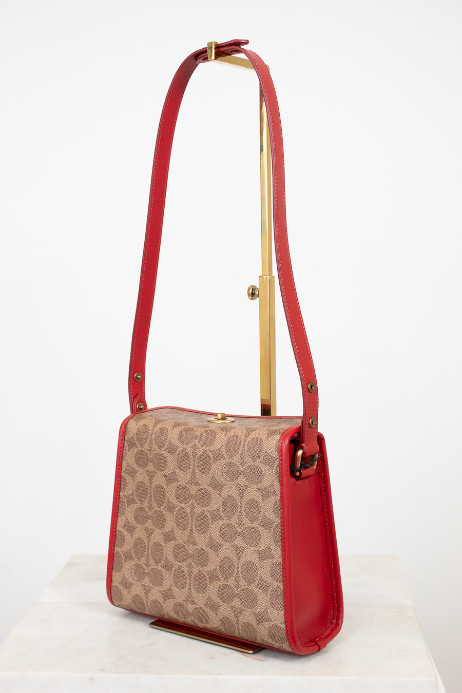 Handbag with red strap and beige pattern on a white background