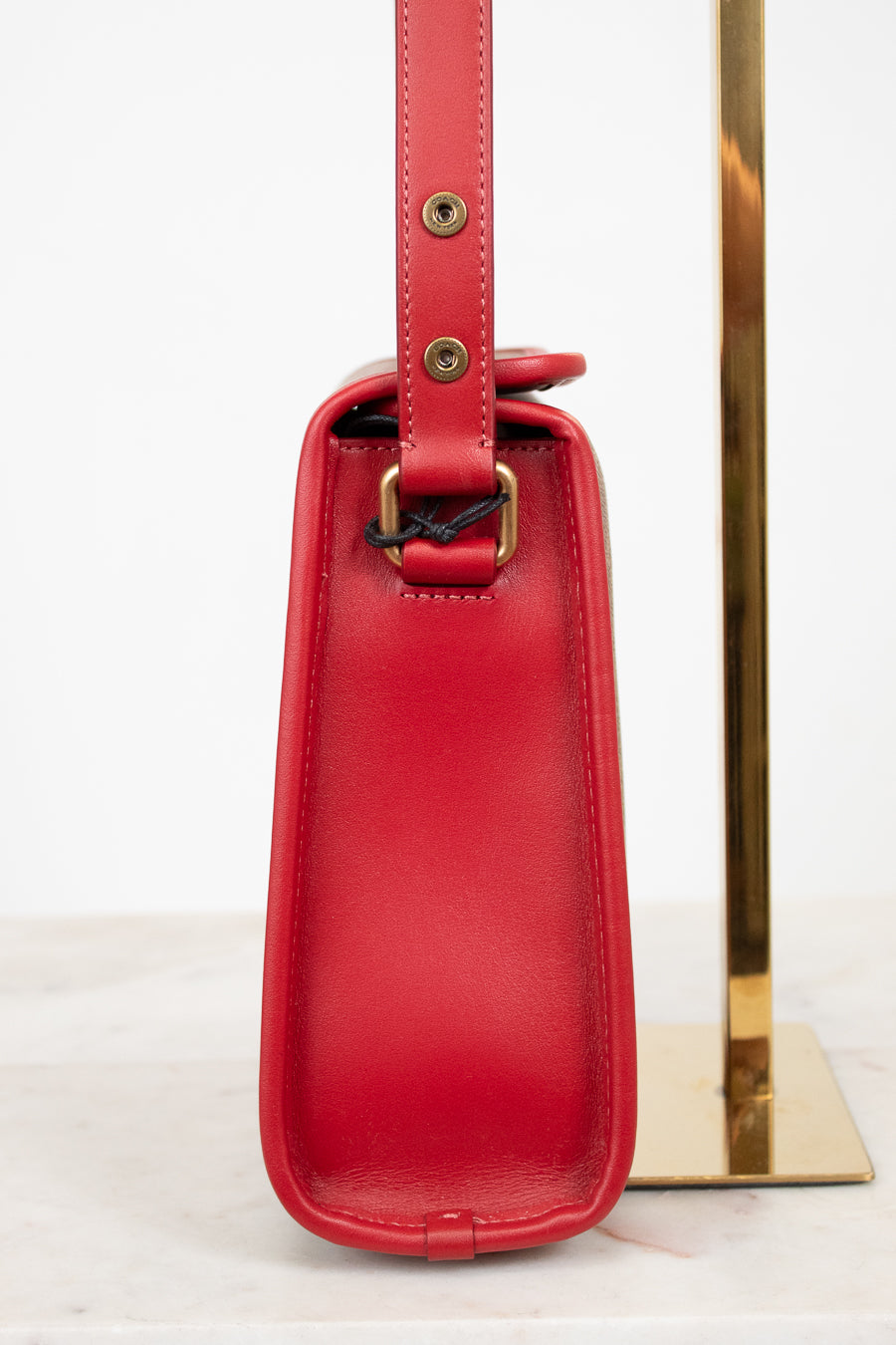 Red handbag with a gold strap on a white background
