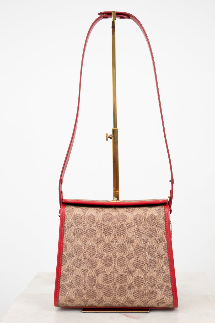 Handbag with red strap and beige pattern on a white background