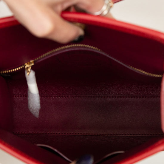 Red handbag with a gold zipper being held open, showing the interior.
