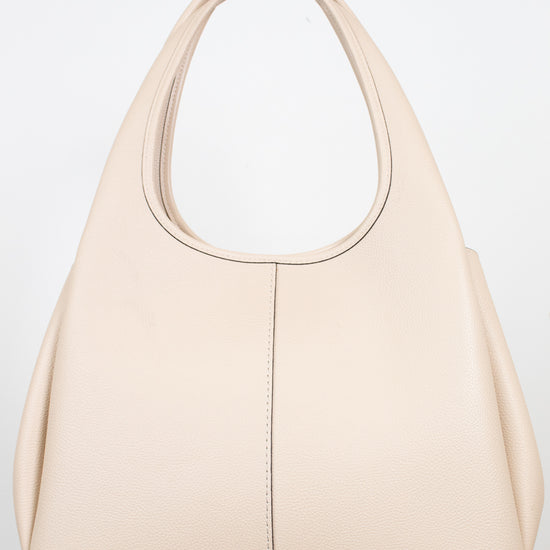 Back view of a  light beige leather shoulder bag  displayed on a light marble surface against a white background.